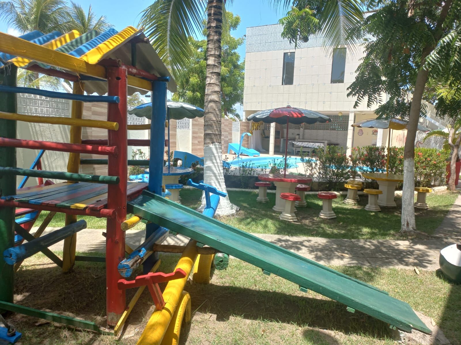 Playground colorido de madeira com escorregador, próximo à piscina